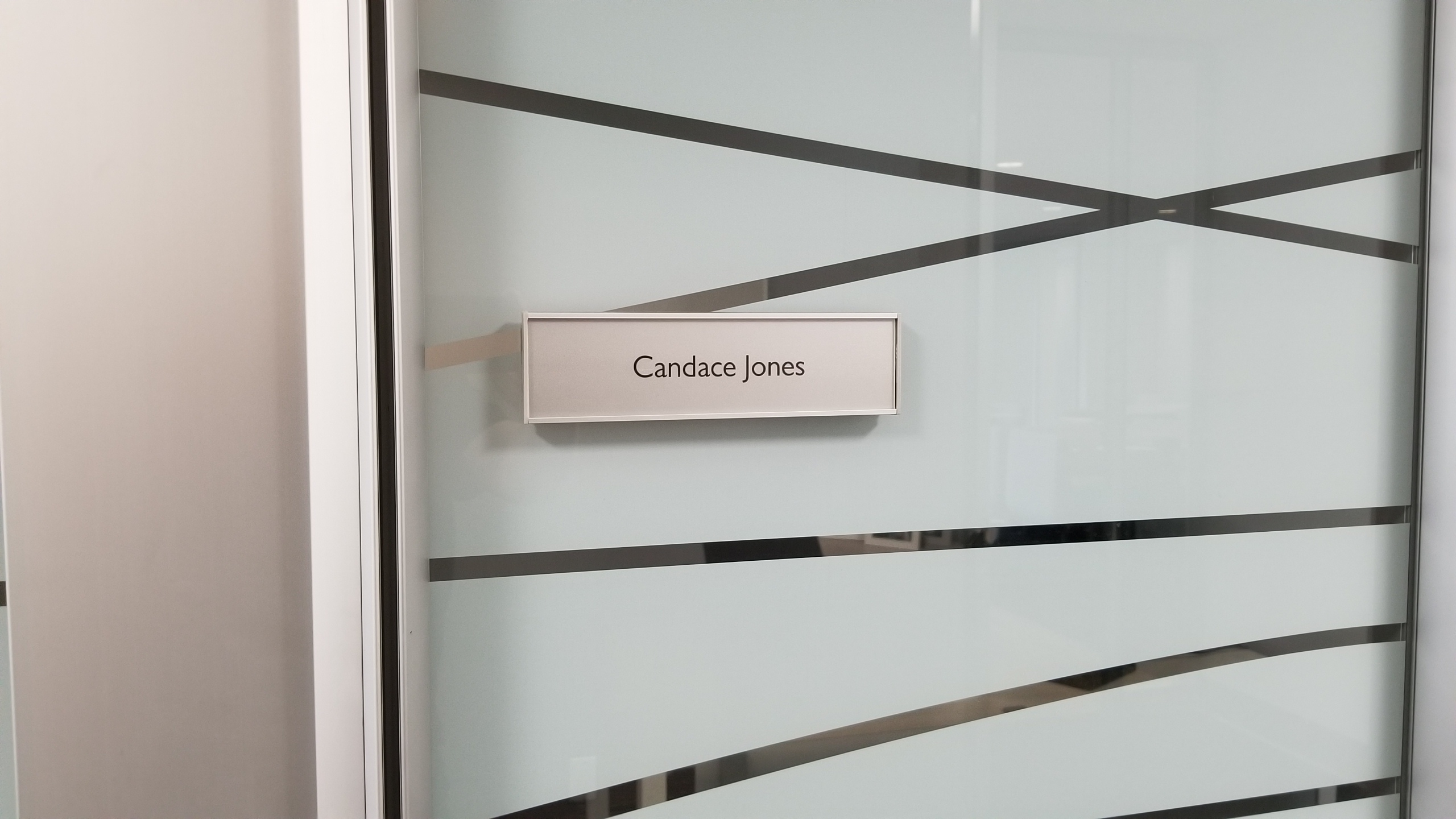 Changeable VSF60-8.5L Flat Office Nameplate installed on glass Candace